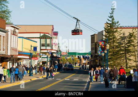 I turisti affollano il Sud Franklin Street come Mount Roberts il tram passa auto overhead in Downtown Juneau, in Alaska Foto Stock