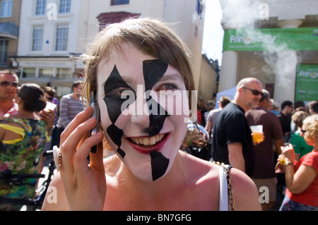 A Brighton Festival Fringe street perfomer in pieno il trucco sul suo telefono cellulare tra mostra in Brighton East Sussex. Foto Stock