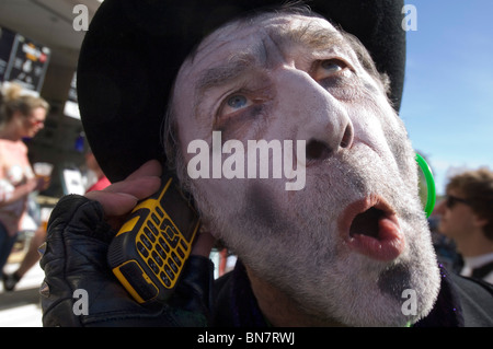 A Brighton Festival Fringe street perfomer in pieno il trucco sul suo telefono cellulare tra mostra in Brighton East Sussex. Foto Stock