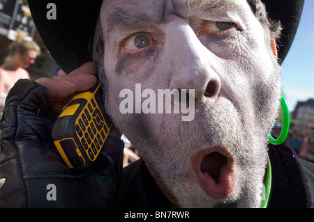 A Brighton Festival Fringe street perfomer in pieno le risposte per il trucco del suo telefono mobile tra mostra in Brighton East Sussex. Foto Stock