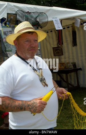 Stallholder con bobina di compensazione, e indossando fatti a mano con fionde attorno al collo a Osmaston Park gioco Country Fair, Derbyshire, Regno Unito Foto Stock