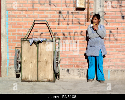 Una donna mangia uno snack in strada a Uyuni vicino al Salar de Uyuni in Bolivia Foto Stock