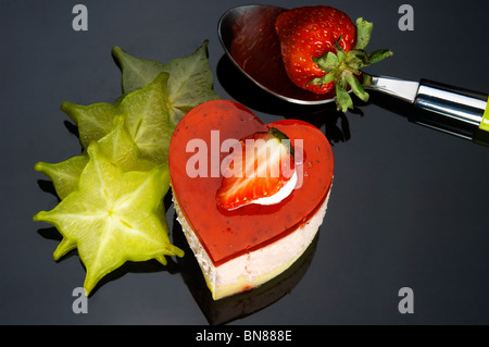 A forma di cuore la torta di fragole con carambola o star fruit decorazione su sfondo nero Foto Stock