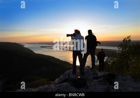 Sagome dei fotografi sulla sommità dei monti Zhiguli al tramonto sul fiume Volga Foto Stock