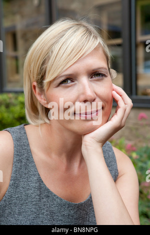 Giovane donna 30s, mano di toccare la faccia Foto Stock