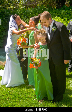Un misto di gara sposa e Caucasico marito abbraccio loro bridesmaids dopo una formale all'aperto cerimonia di nozze, arancio, CA MODELLO DI RILASCIO Foto Stock