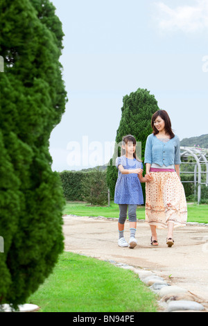 Ragazza camminare con la madre mano nella mano Foto Stock