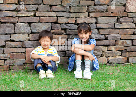 Ritratto di ragazzo e una ragazza seduta da un muro di mattoni Foto Stock