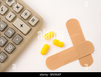 Calcolatrice elettronica con le pillole di giallo e due cerotti isolato su bianco Foto Stock