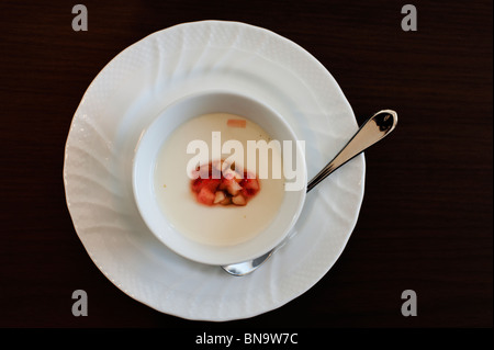 Panna cotta guarnita con fragole fresche al buio su un tavolo di legno. Foto Stock