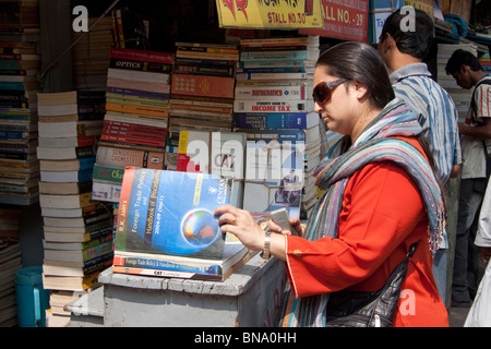 Una signora accede attraverso un libro in un negozio su College Street in Kolkata (Calcutta), West Bengal, India. Foto Stock