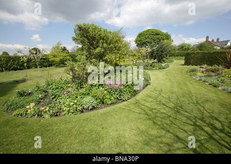 Bluebell Cottage Gardens, Inghilterra. Molla generale vista di Bluebell Cottage Gardens frontiere, arbusti e biancheria da letto. Foto Stock