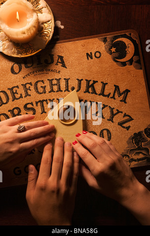 Primo piano delle mani su Ouija board Foto Stock