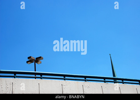 Parcheggio in garage con luci di strada sulla parte superiore e il campanile in background contro il cielo blu e chiaro. Foto Stock