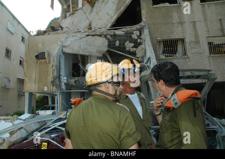 Ufficiali israeliani dalla casa di comando stand in mezzo alle macerie di un edificio residenziale distrutto dopo che ha sostenuto un colpo diretto da un razzo Hezbollah Grad nel quartiere di Bat Galim nella città di Haifa durante la guerra Israele - Hezbollah Foto Stock