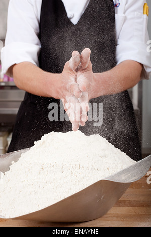 Lo chef maschio farina di sfregamento sulle mani in cucina commerciale Foto Stock