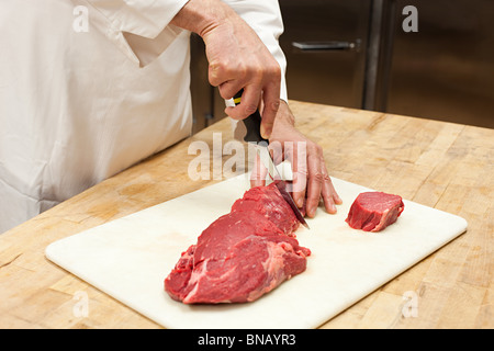 Lo chef maschio preparare la carne in cucina commerciale Foto Stock