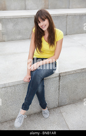 Giovane donna seduta sul gradino Foto Stock