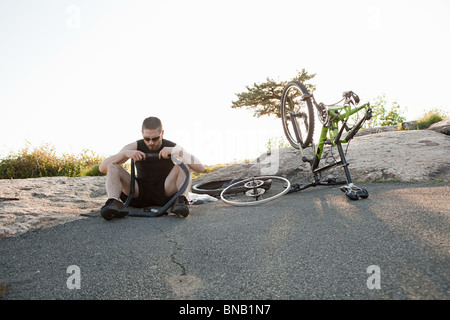 Ciclista maschio che fissa pneumatico forato Foto Stock