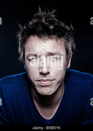 Ritratto in studio su sfondo nero di un divertente espressiva uomo caucasico addormentato Foto Stock