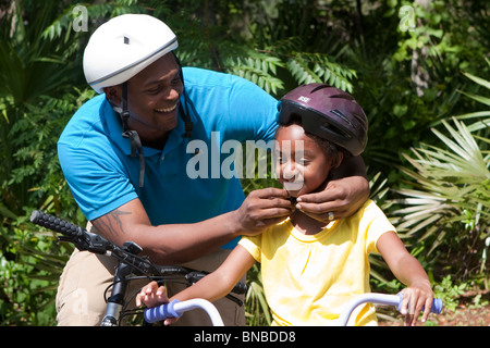 Padre mettendo il casco protettivo sulla figlia Foto Stock