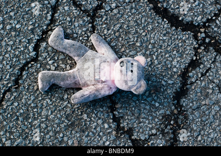Una rosa orsacchiotto di peluche si trova abbandonato e sporco sul ciglio della strada. Foto Stock