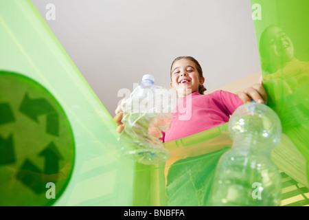 Ragazza con bottiglie di plastica per il riciclaggio, visto dal lato interno del contenitore di riciclaggio. Spazio di copia Foto Stock