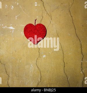 Cuore di carta fissato su una parete incrinata. Foto Stock