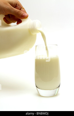 Versando un bicchiere di latte da una caraffa di plastica Foto Stock