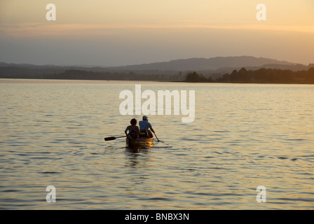 Matura in una barca a remi sul lago al tramonto, Murnau am Staffelsee, Garmisch-Partenkirchen, Alta Baviera, Baviera, Germania Foto Stock