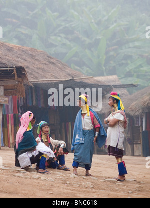 Quattro donne dal Padaung lungo collo della tribù della collina di parlare ad un altro in un villaggio vicino a Tha Ton, Chiang Mai Provincia, Thailandia Foto Stock