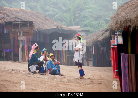 Quattro donne dal Padaung lungo collo della tribù della collina di parlare ad un altro in un villaggio vicino a Tha Ton, Chiang Mai Provincia, Thailandia Foto Stock