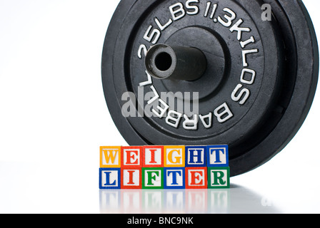 Bambini colorati blocchi del peso di ortografia LIFTER con barbell pesi in background Foto Stock