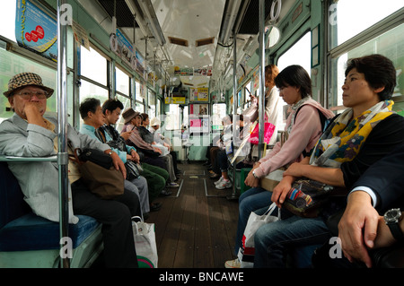 Le persone viaggiano in un vecchio tram in Kumamoto, Prefettura di Kumamoto, Regione di Kyushu, Isola di Kyushu, Giappone Foto Stock