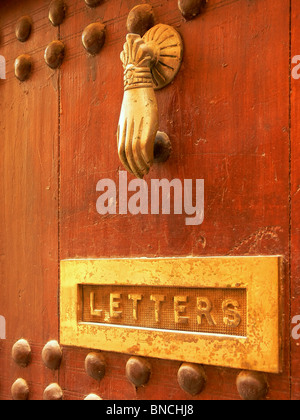 Porta in ottone respingente su una vecchia porta rossa a Marrakech, Marocco Foto Stock