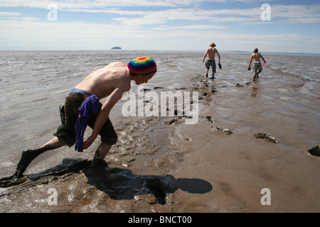 Gruppo di ragazzi trascinarsi faticosamente attraverso il fango durante la bassa marea, Weston-Super-Mare, Regno Unito Foto Stock