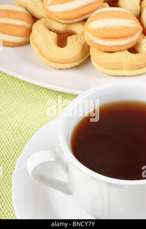 Close-up di una tazza di tè, un po' di pasta frolla biscotti su uno sfondo verde chiaro Foto Stock
