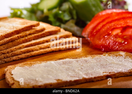 Fette di Melba toast, uno adagiate su una piastra con insalata fresca. Foto Stock