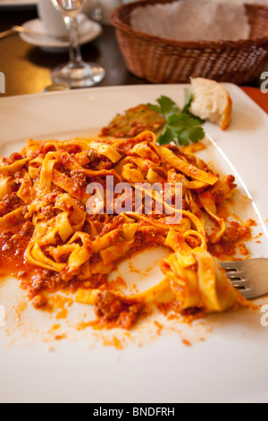 Tagliatelle con salsa di ragù su un piatto, porzione mangiata a metà Foto Stock