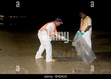 Due uomini in sacchi di olio di catrame e di notte da un Mississippi Beach, durante la BP fuoriuscite di olio. Luglio, 2010. Foto Stock