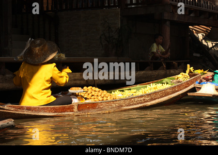 Mercato Galleggiante di Damnoen Saduak in Thailandia, donna in giallo in una canoa pieno di frutta Foto Stock