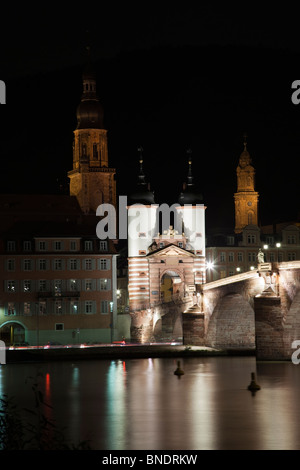 Centro storico di Heidelberg Bridge bella di notte le luci, riflessioni in morbido che scorre sul fiume Neckar, acqua torri della chiesa sfondo nero Baviera Germania Foto Stock