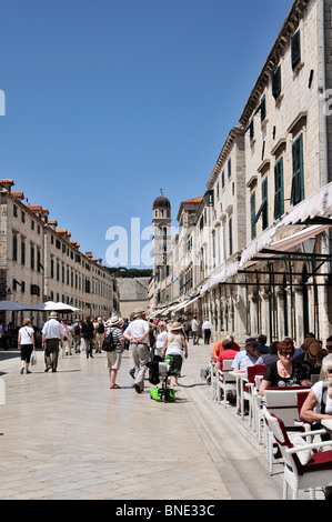 I turisti passeggiare tra le uniformi di architettura barocca del case, negozi e ristoranti all'aperto in Placa Stradun, Dubrovnik Foto Stock