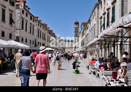 I turisti passeggiare tra le uniformi di architettura barocca del case, negozi e ristoranti all'aperto in Placa Stradun, Dubrovnik Foto Stock