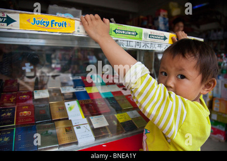 Bambina presso il contatore di sigarette della sua famiglia convenicence store in Xingping, provincia di Guangxi, Cina Foto Stock