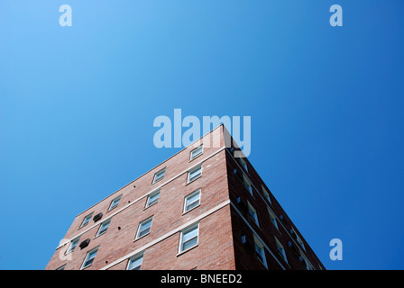 Guardando verso l'alto edificio di mattoni rossi contro il cielo blu. Foto Stock