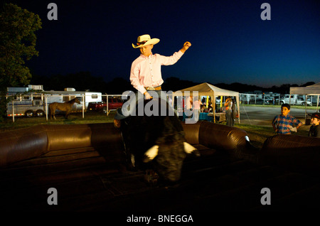 Cowboy cercando la sua fortuna a rimanere sul toro meccanico Foto Stock