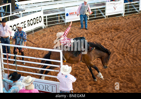 Cavallo cercando di gettare il rodeo cowboy membro di PRCA dalla sua parte posteriore in Smalltown Bridgeport Texas, Stati Uniti d'America Foto Stock