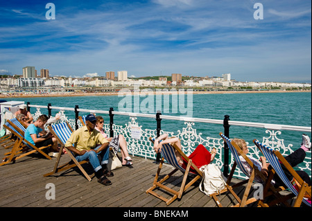 Persone in rilassanti sedie a sdraio sul molo, Brighton East Sussex, Regno Unito Foto Stock