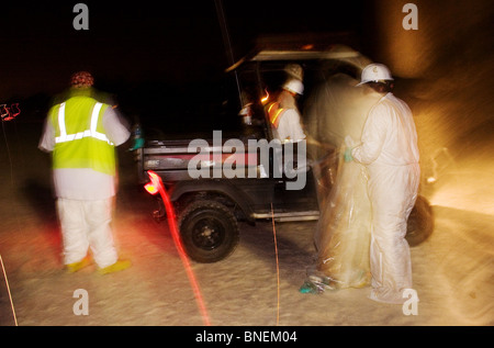 Tempo di esposizione 3 gli operatori sanitari la pulizia di fuoriuscite di olio pasticcio di notte su una spiaggia del Mississippi. Luglio 2010. Foto Stock